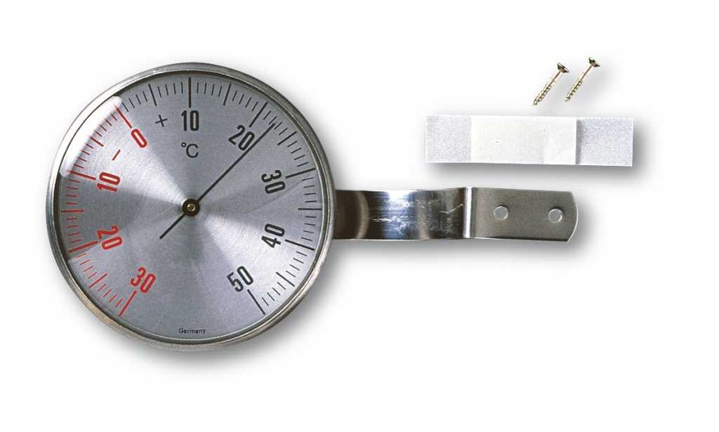 Rundes Analogthermometer aus Metall mit Befestigungslasche, daneben zwei Schrauben und Klebepad auf weißem Hintergrund