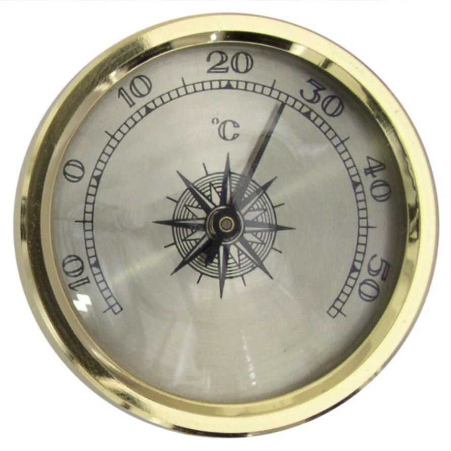Rundes Thermometer mit goldfarbenem Rand, Skala in °C und schwarzem Zeiger auf silbernem Zifferblatt mit Kompassrose